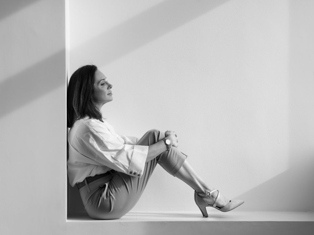 Czarno-biały portret kobiety w słonecznym wnętrzu – spojrzenie w stronę okna