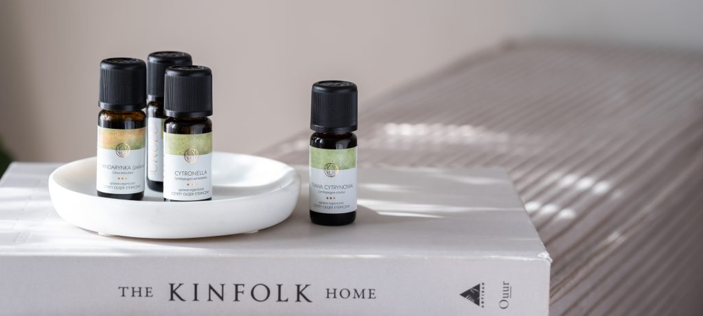 olejki eteryczne w naturalnym domu, stoją na książce kinfolk home - przez okno wpada słońce. - sesja produktowa Warszawa