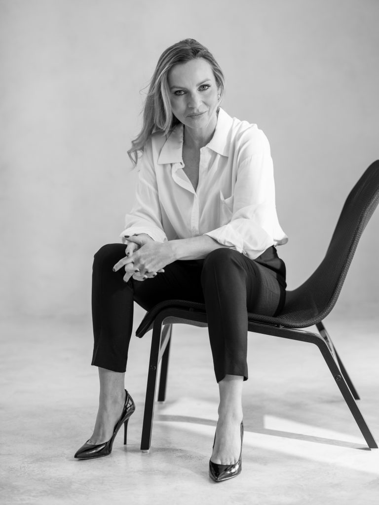 silna, zdecydowana kobieta siedząca na krześle - czarno białe zdjęcie w białej koszuli