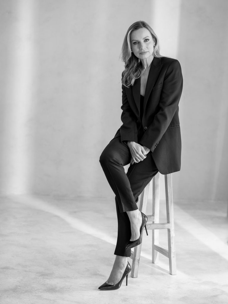 kobieta w garniturze siedząca na wysokim stołku