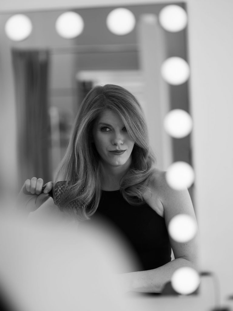 kobieta przeglądająca się w lustrze czesząca włosy