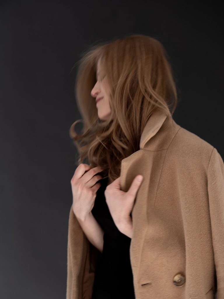 śmiejąca się kobieta w brązowym płaszczu